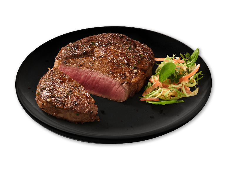 Grillet bøf med salat på en sort tallerken.