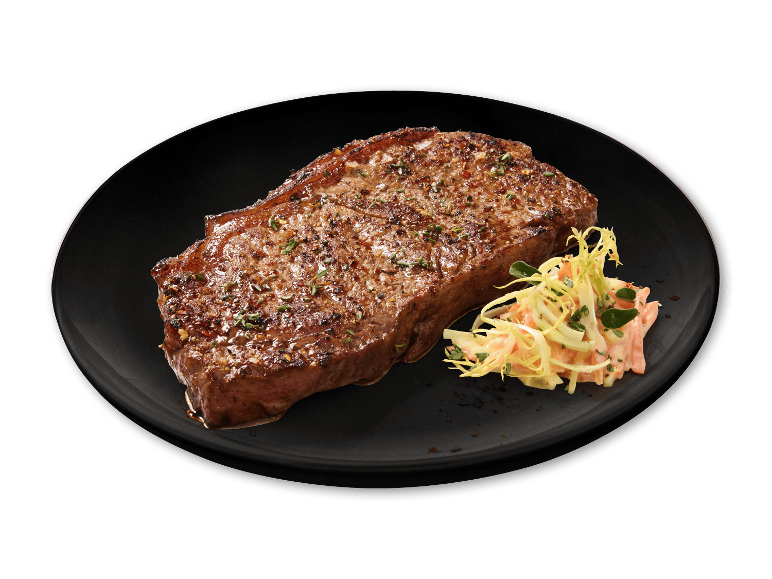 Grillet bøf med krydderurter og coleslaw på en sort tallerken.