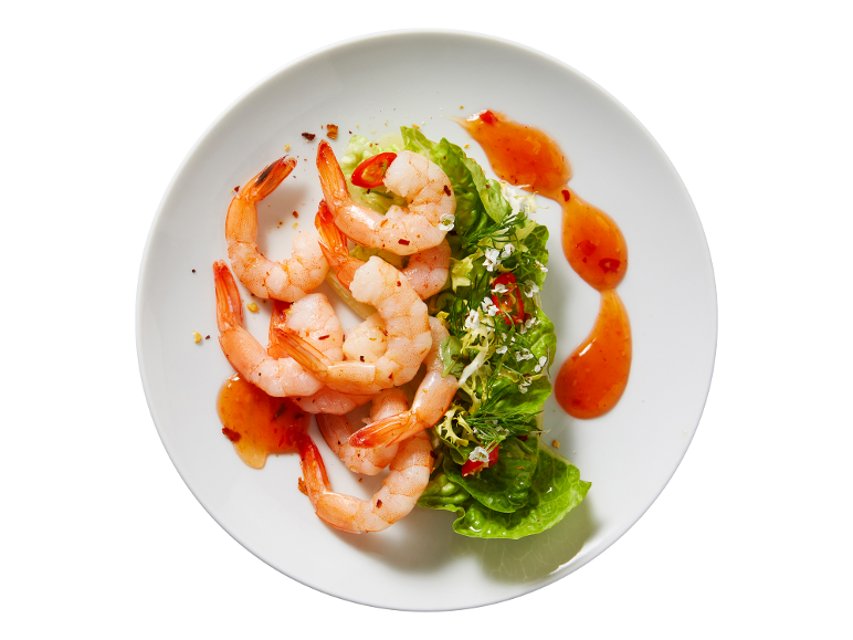 Rejer med salat og sød chilisauce på en hvid tallerken.