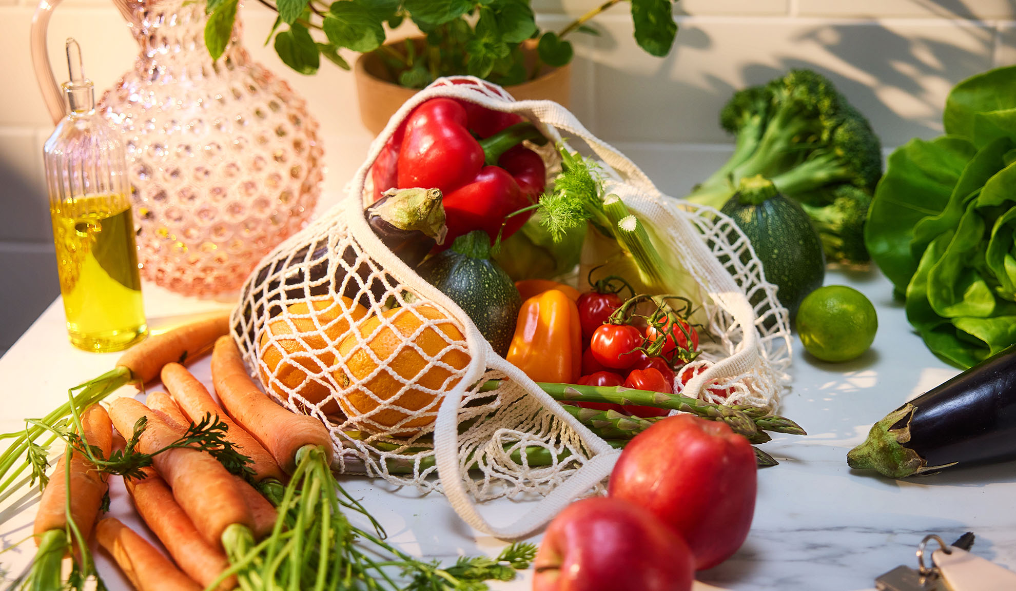Friske grøntsager og frugter, som peberfrugter, appelsiner og gulerødder, i en indkøbspose.