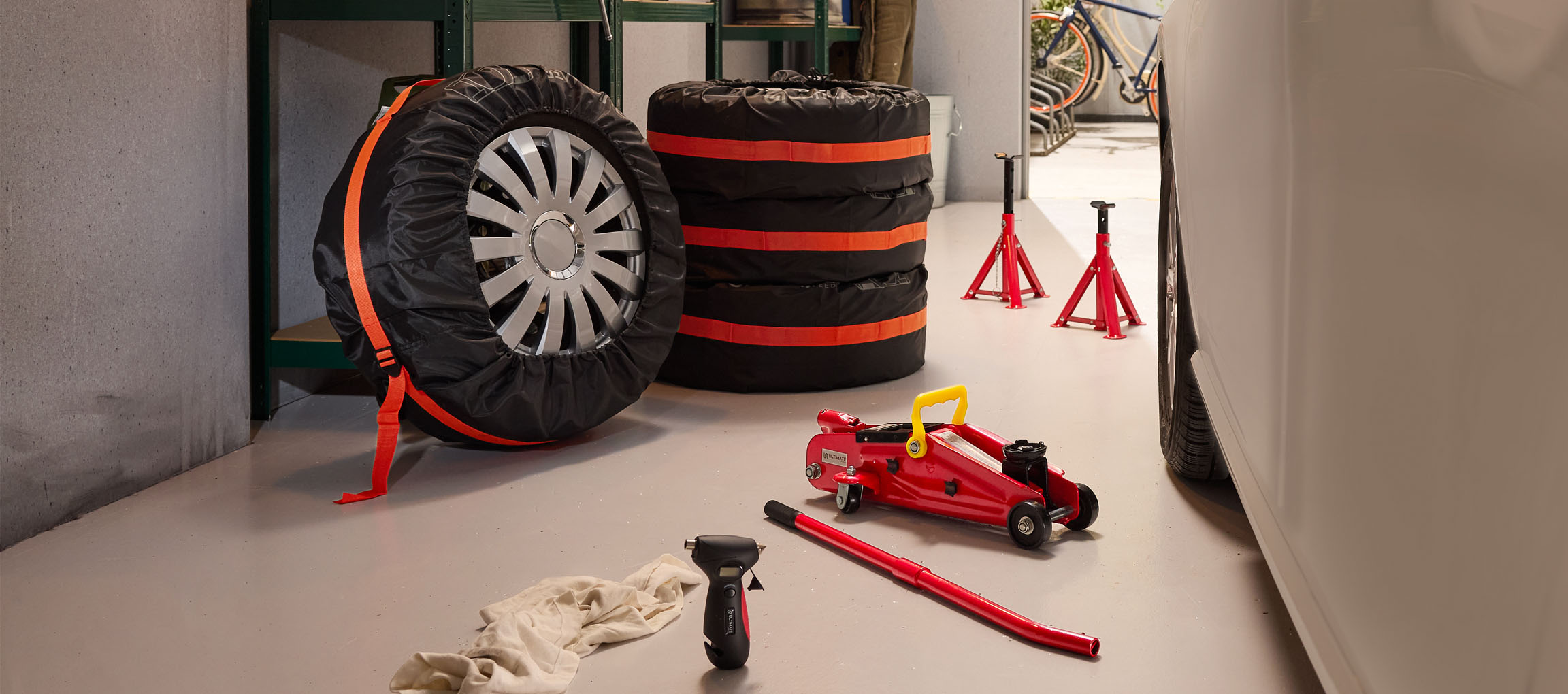 Bildæk med overtræk, donkraft og støttebukke i en garage.