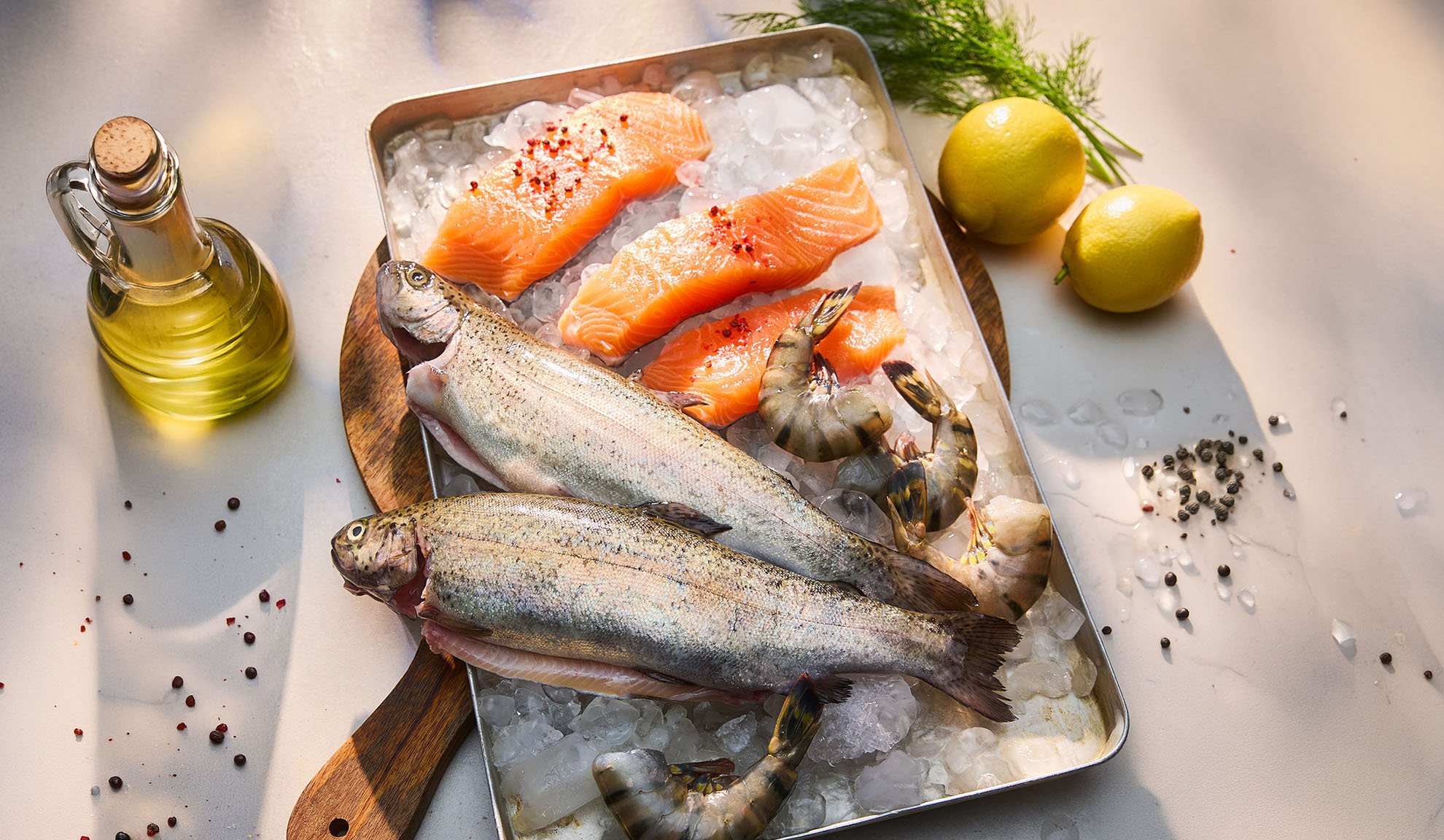 Frisk fisk, laksefileter og rejer på is, med citroner og olie.