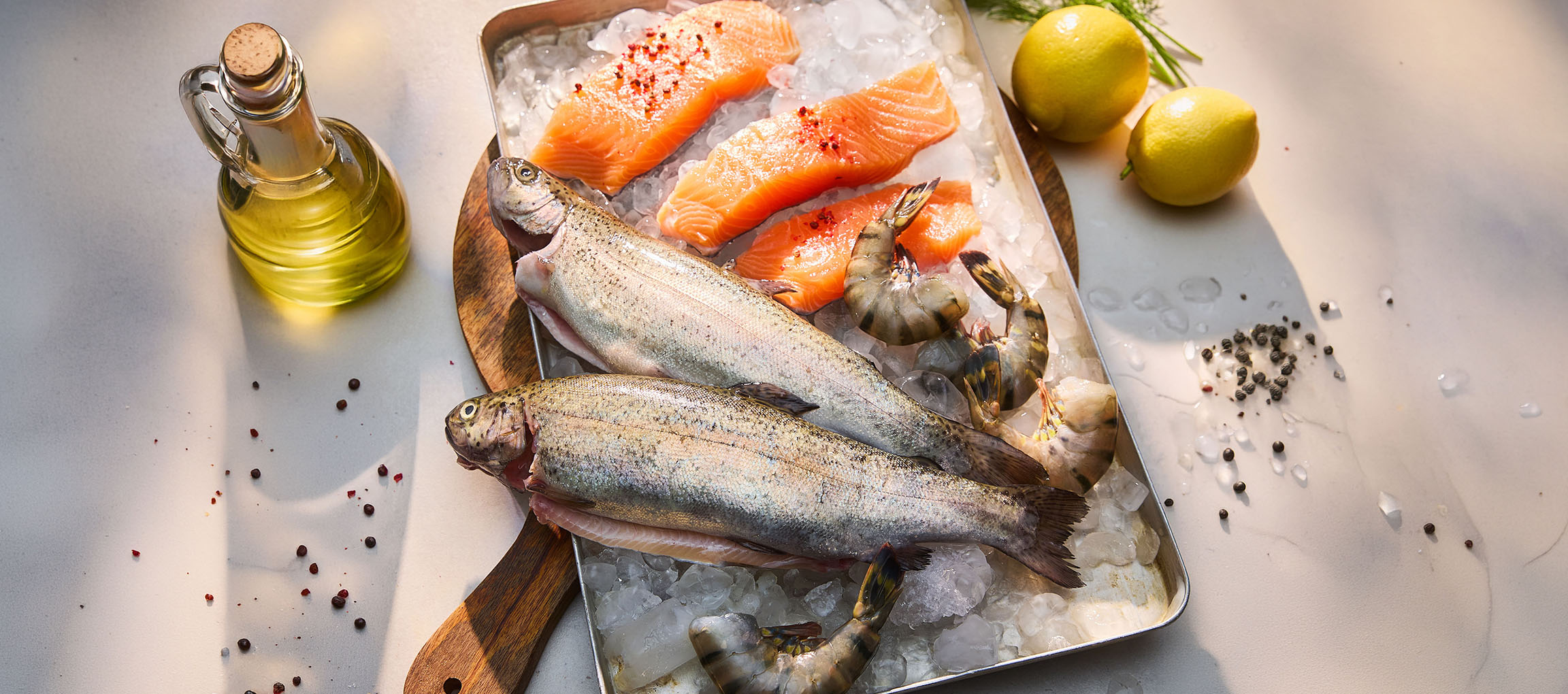 Frisk fisk og skaldyr på is, med citroner og olie.