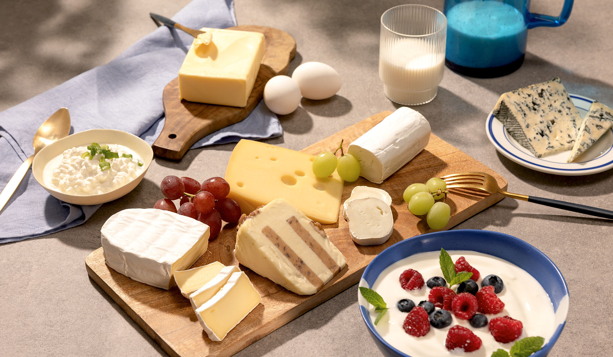 Et udvalg af oste, druer og mejeriprodukter som hytteost, mælk og yoghurt med bær.