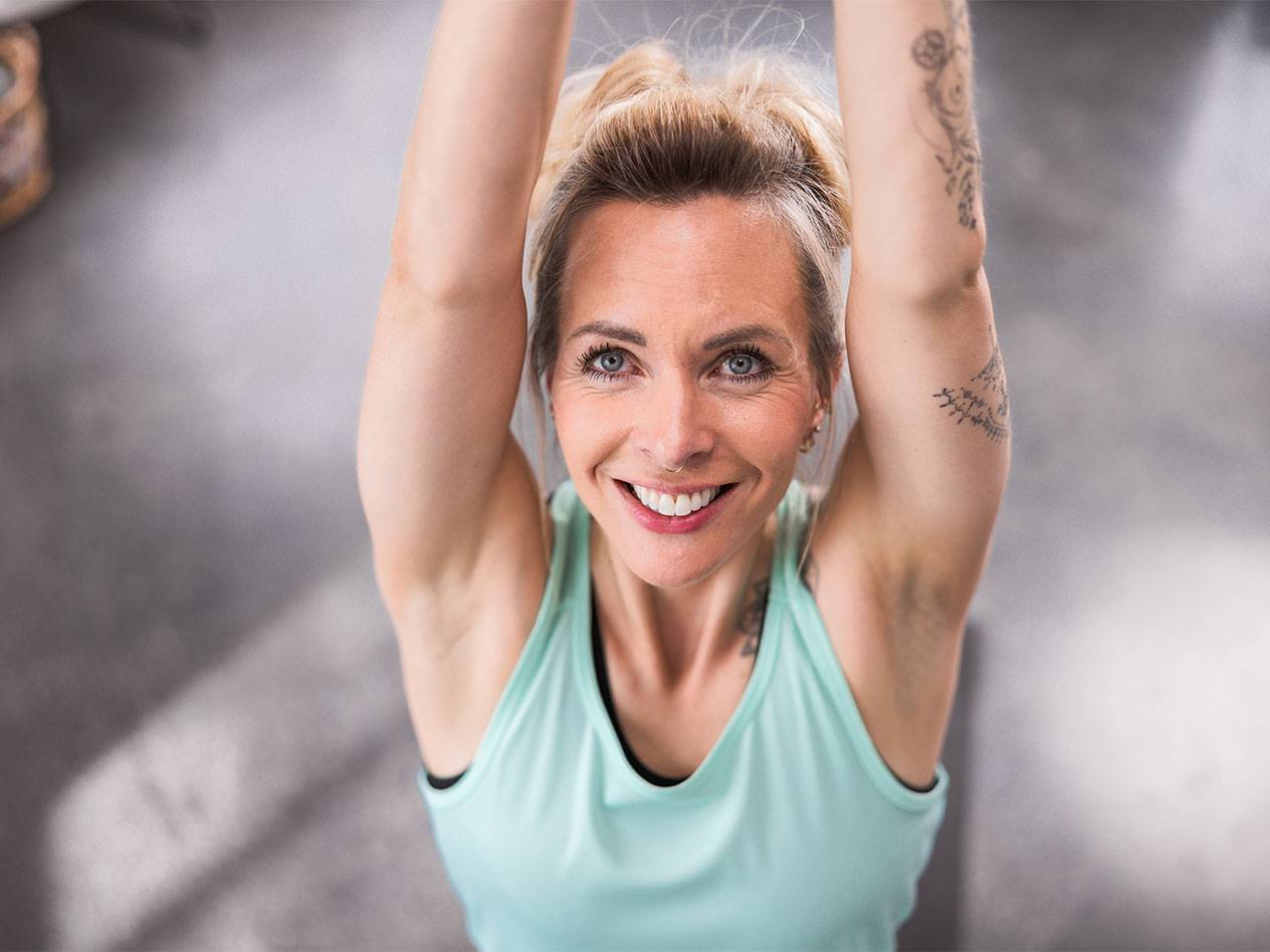 Blond kvinde i en lyseblå tanktop smiler til kameraet.