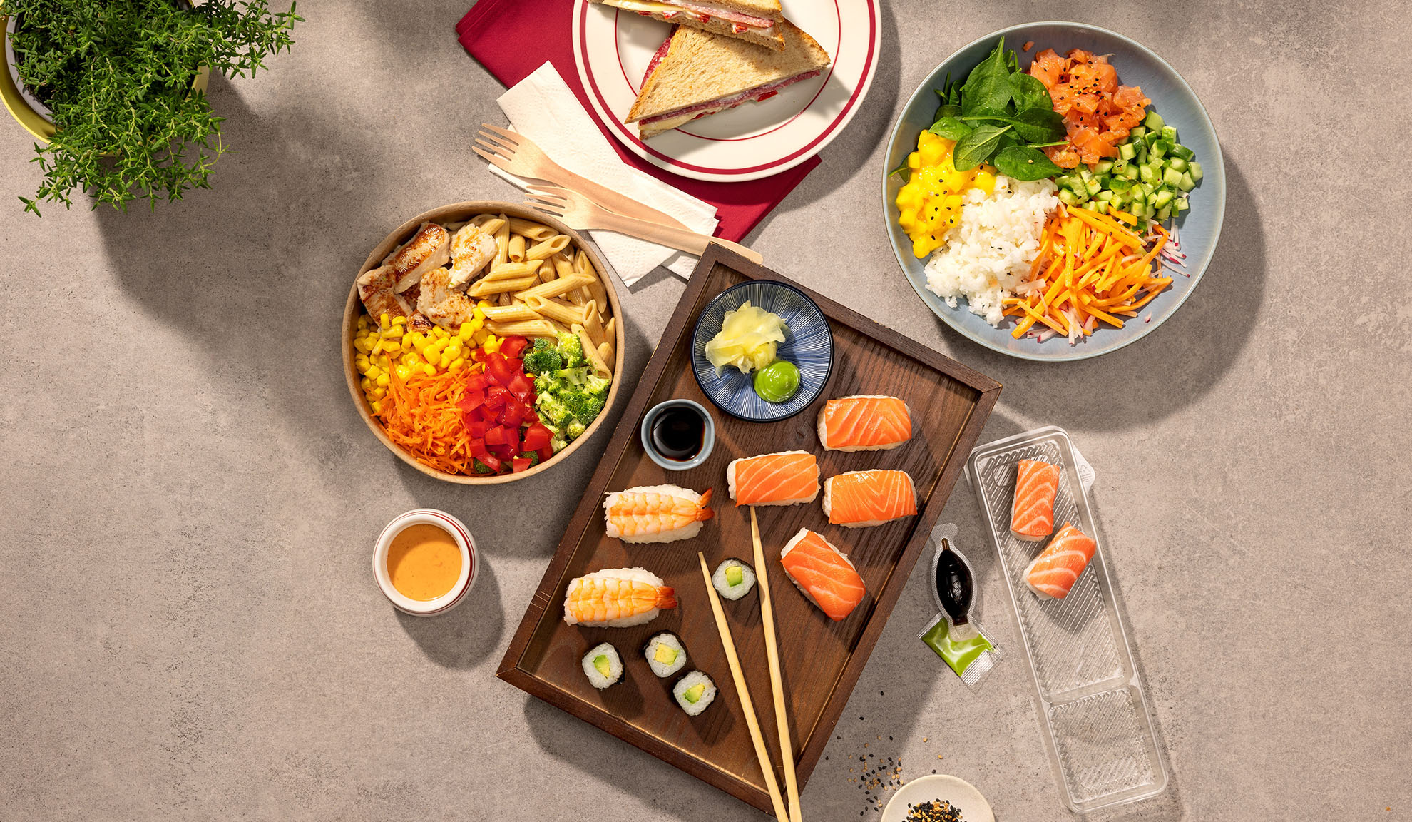 Oversigtsbillede af forskellige takeaway-måltider: sushi, poke bowl, pastasalat og sandwich.