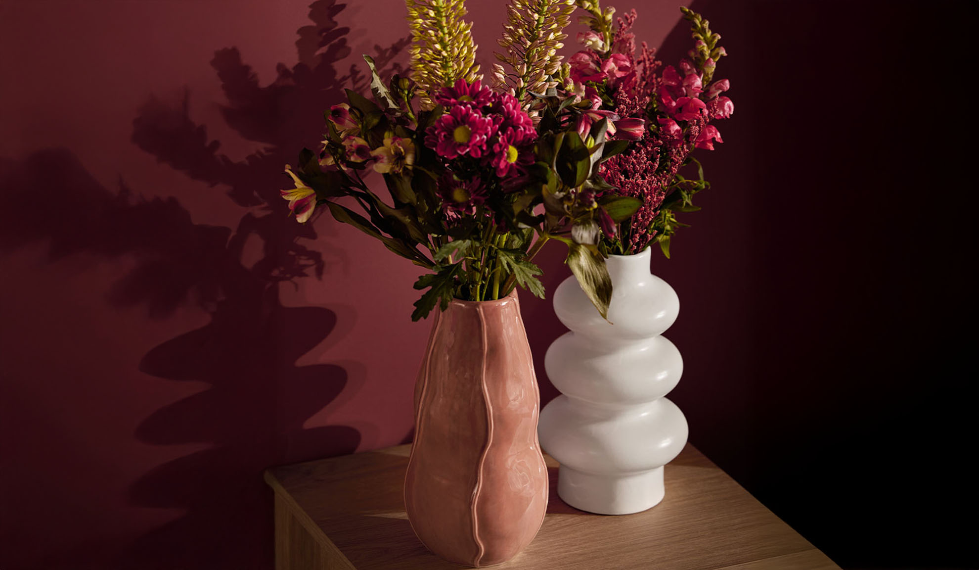 To vaser med farverige blomster på et træbord.