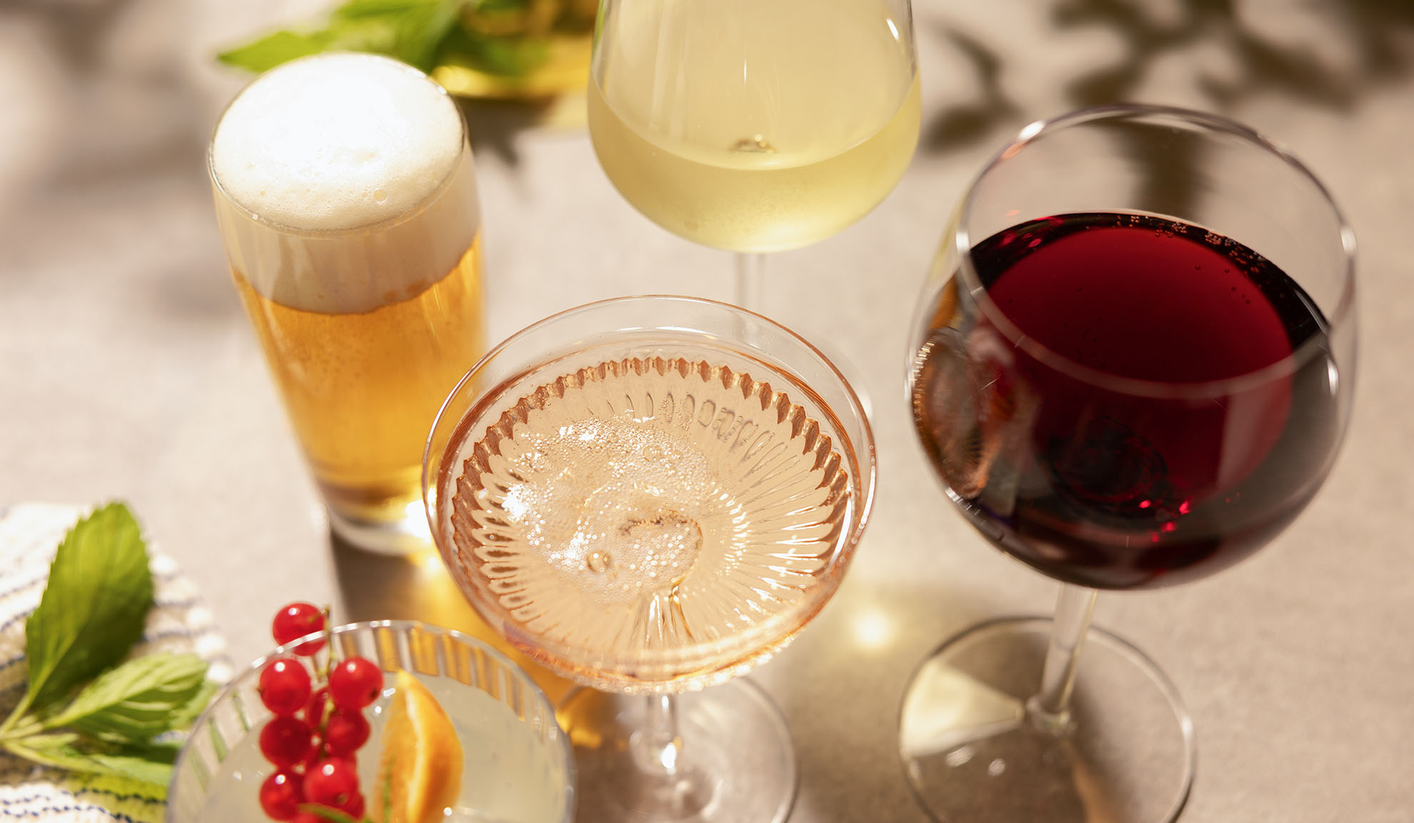 Glas med øl, hvid-, rosé- og rødvin, med en cocktail og bær.