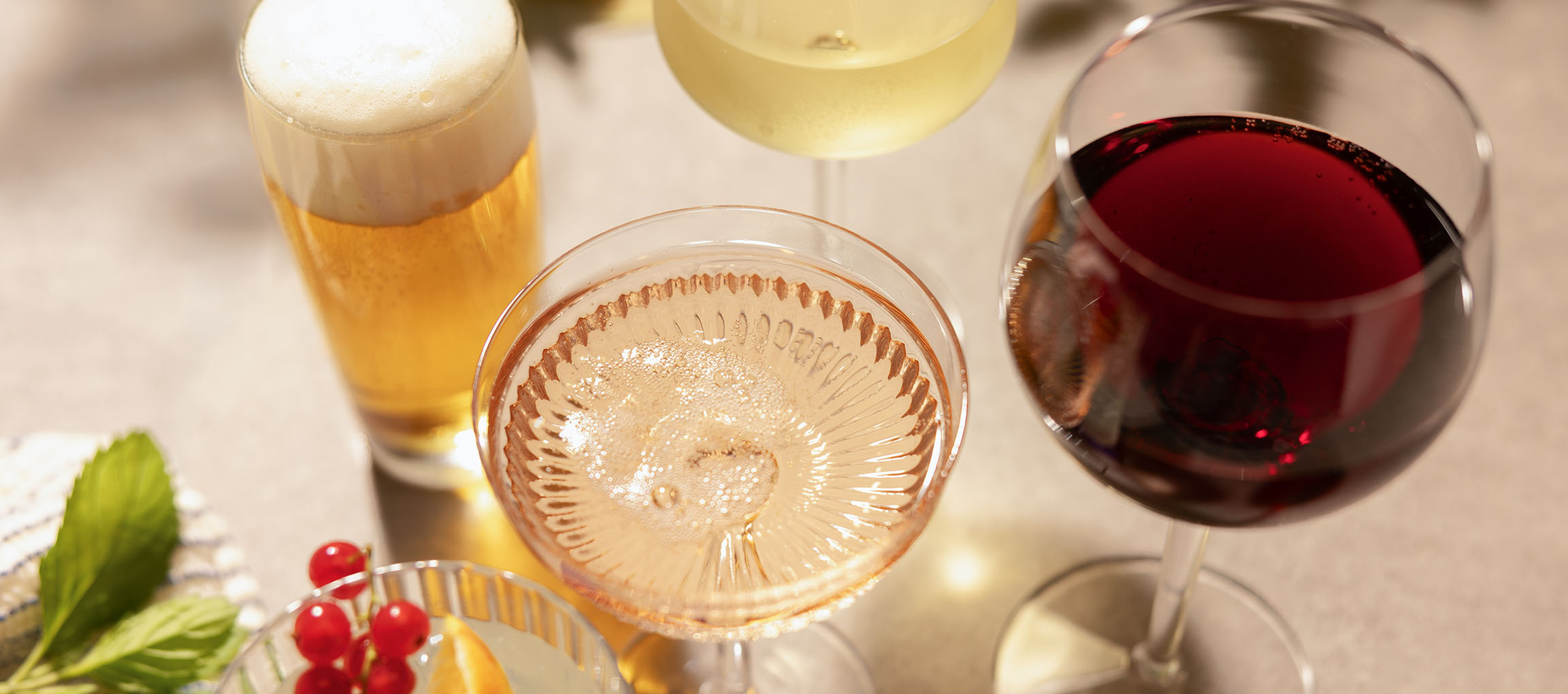 Øl, rosévin og rødvin i glas, med bær og mynte.