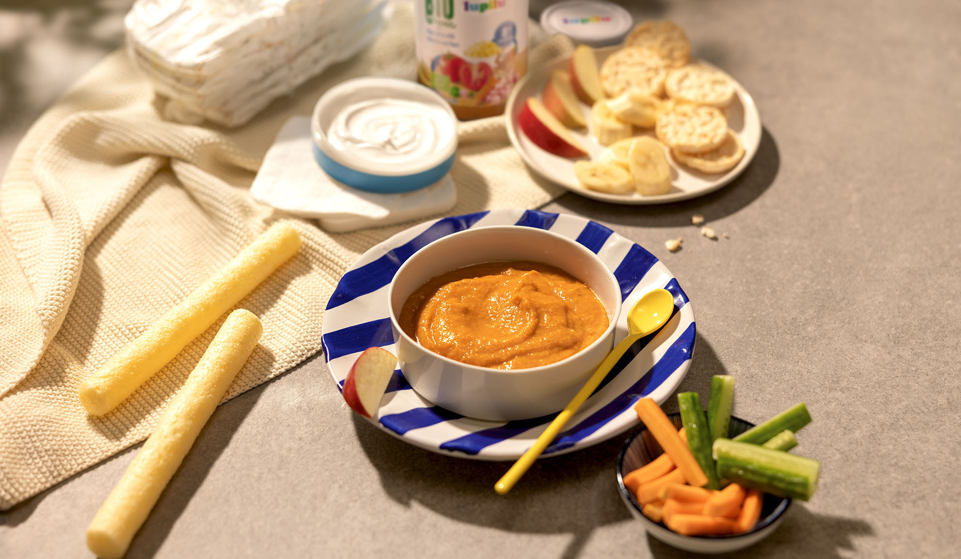 Babymad, yoghurt, skåret frugt og grøntsager, kiks og snacks på et bord.
