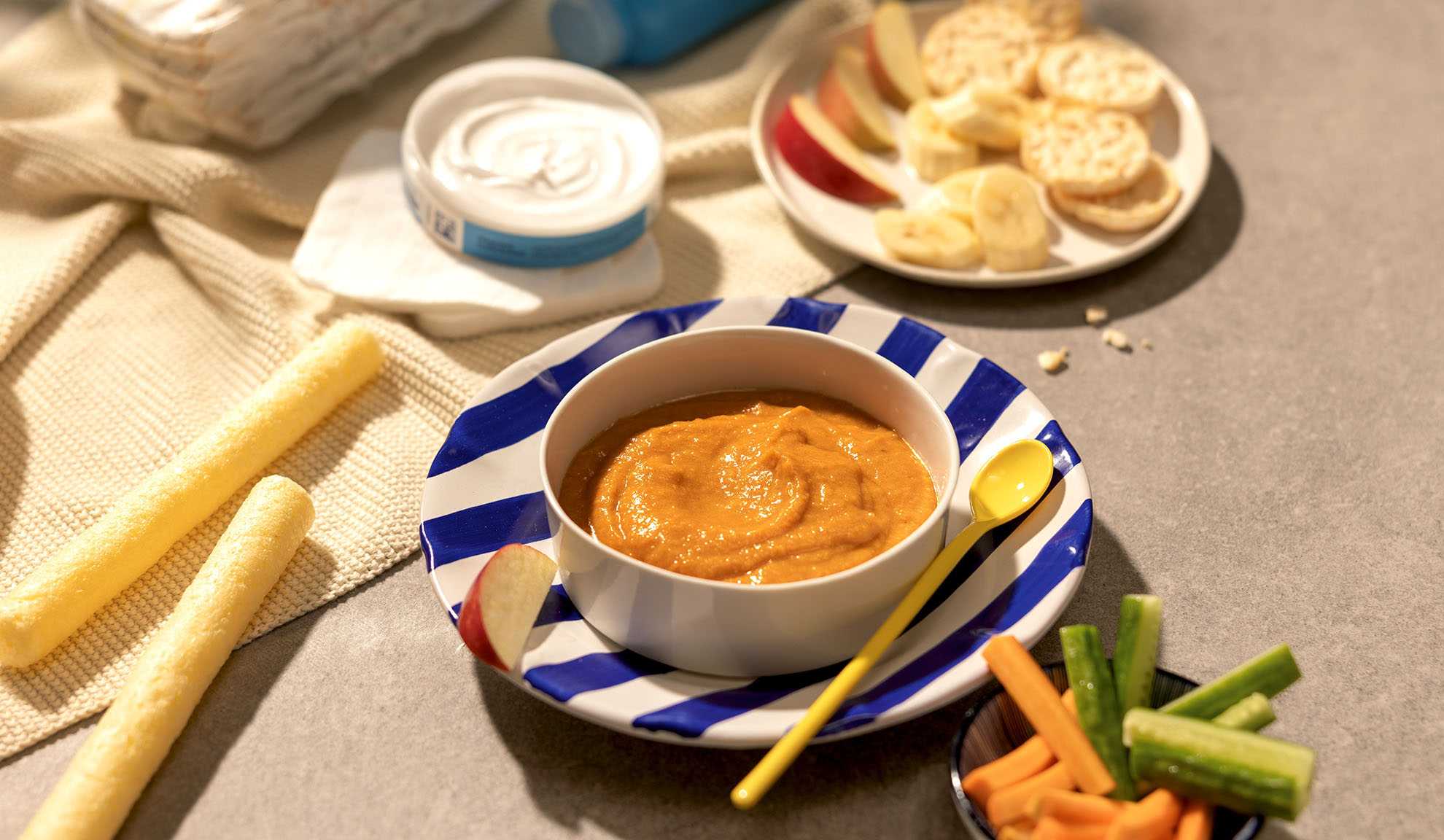 Babymad: skål med puré, frugt, stænger og grøntsager på bordet.