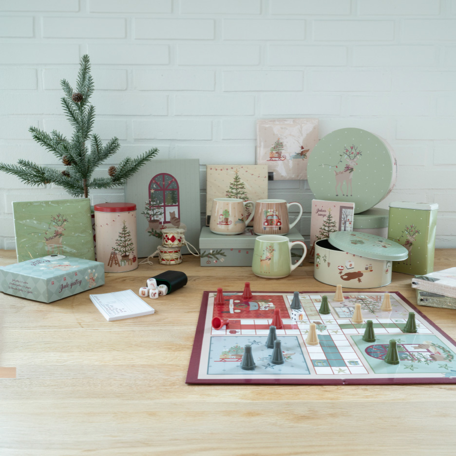 Julepynt og spil, herunder et brætspil, krus og opbevaringsdåser med julemotiver.