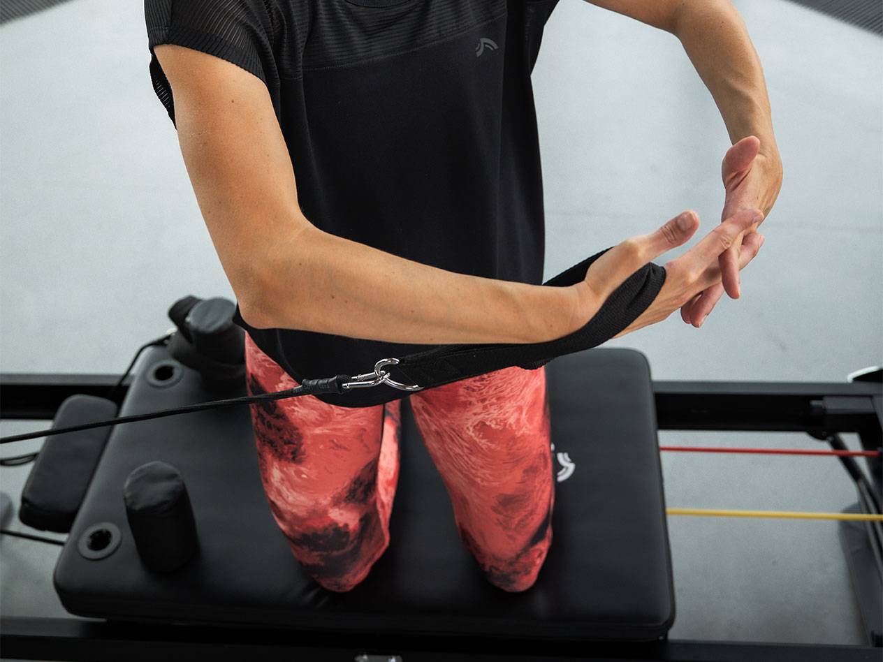 Kvinde træner med modstandsbånd på en Pilates-maskine.