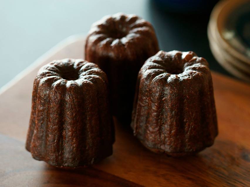 Tre canelés de Bordeaux på et træbræt.