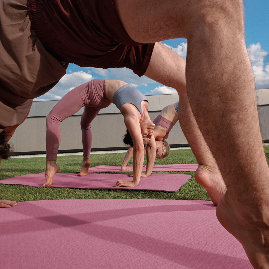 Folk dyrker yoga udendørs på yogamåtter, iført sportstøj.