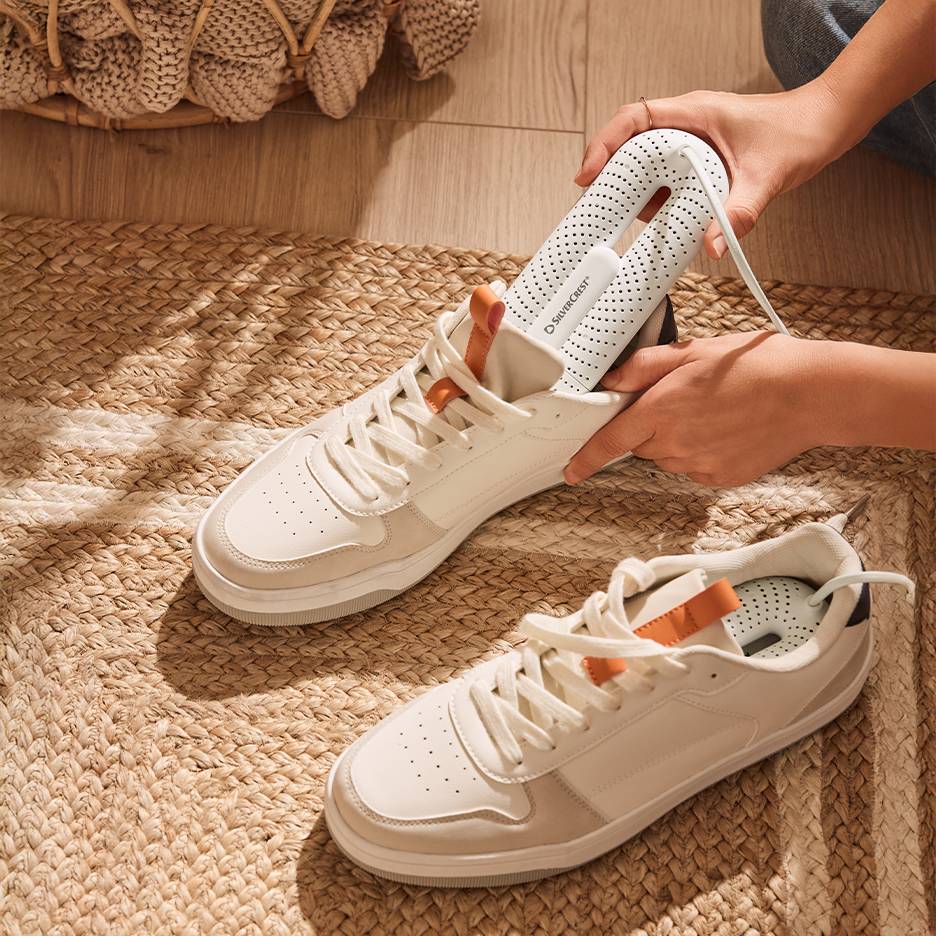 Silvercrest skotørrer i hvide sneakers på et flettet tæppe.