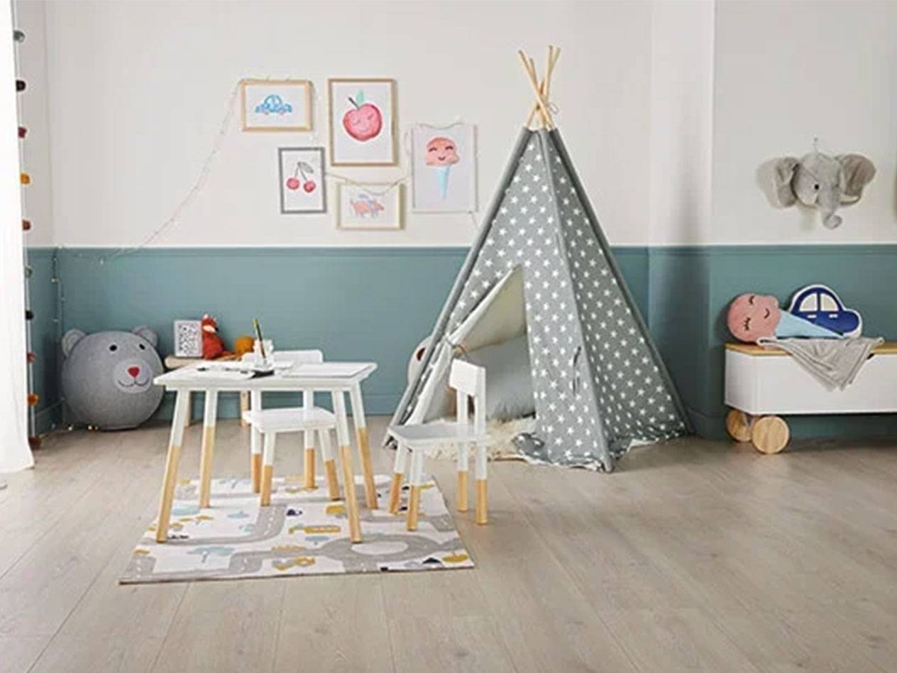 Børneværelse med tipi-telt, bord og stole, legetøjskiste og billeder på væggen.