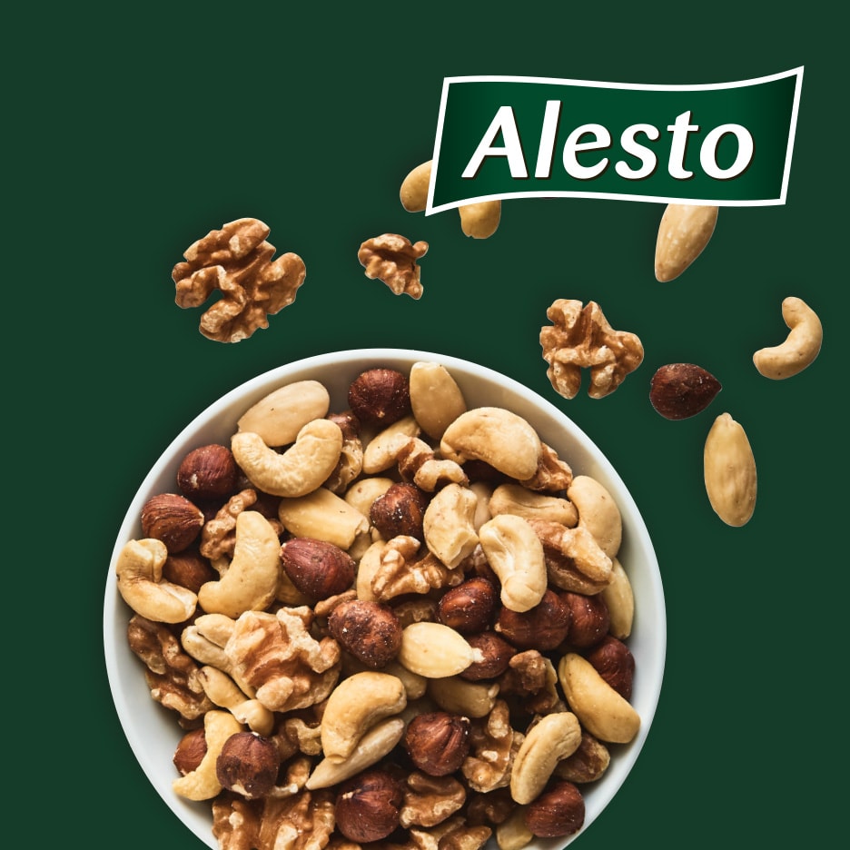 En skål med blandede nødder, herunder cashewnødder, hasselnødder og valnødder, på en mørkegrøn baggrund.