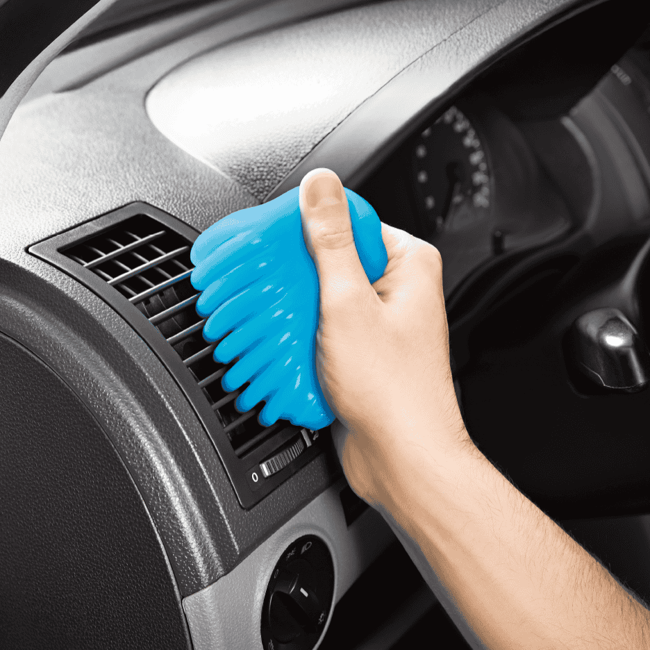 Hånd der renser bilens luftventil med blåt rengøringsslim.