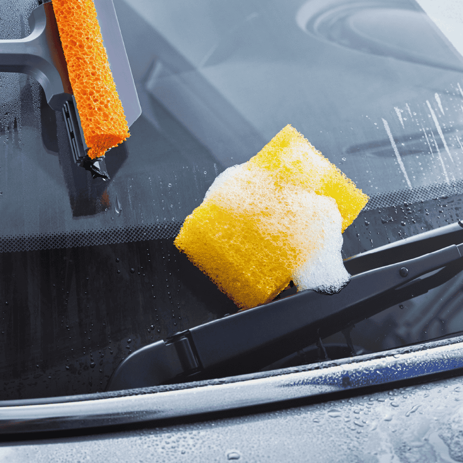 Bilvask med svamp og skraber på forruden.