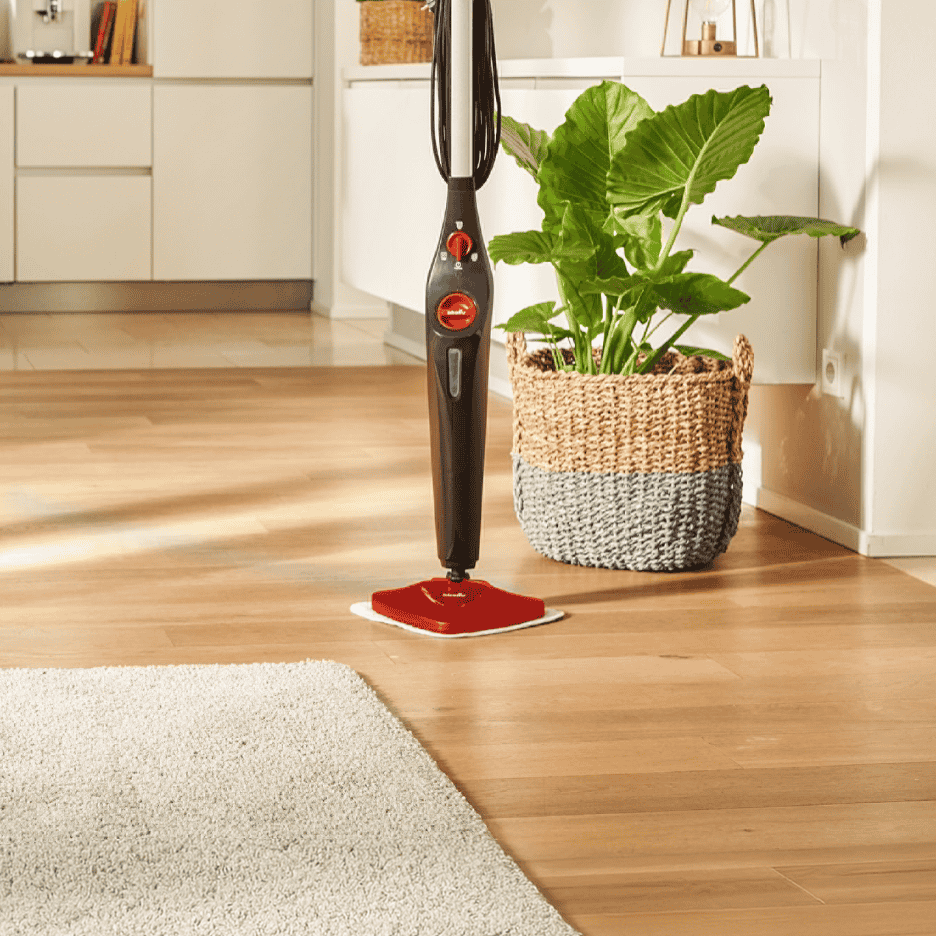 Dampmoppe på et trægulv i et køkken med en plante i en flettet kurv.