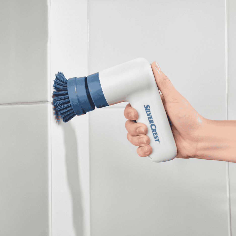 Håndholdt elektrisk skrubber med blåt børstehoved, der rengør flisefuger.