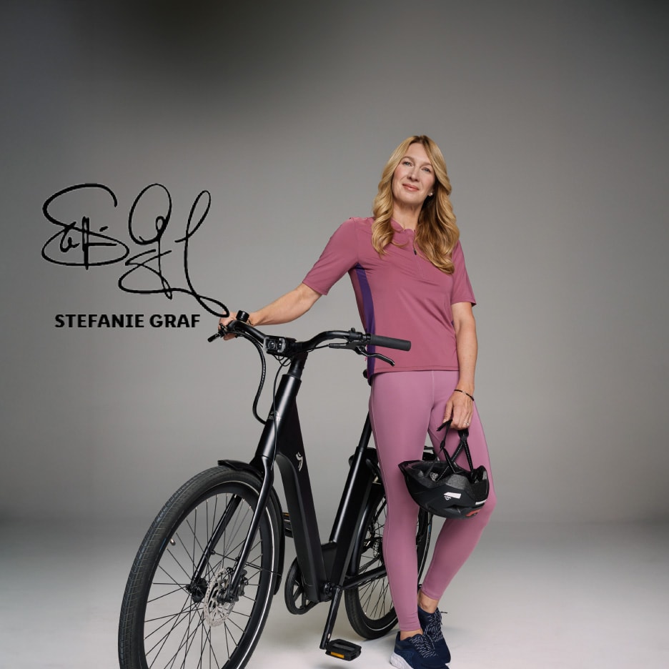 Kvinde i sportstøj med en elcykel og en cykelhjelm, med autograf og navnet Stefanie Graf.