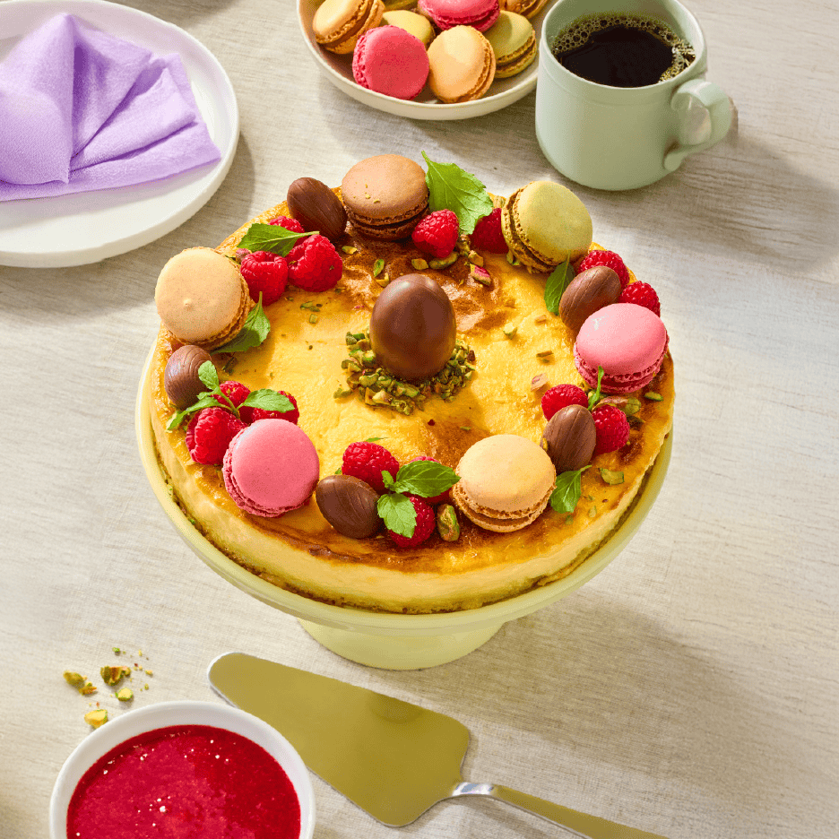 Cheesecake med makroner, chokoladeæg, hindbær og mynte, serveret med kaffe og hindbærsauce.