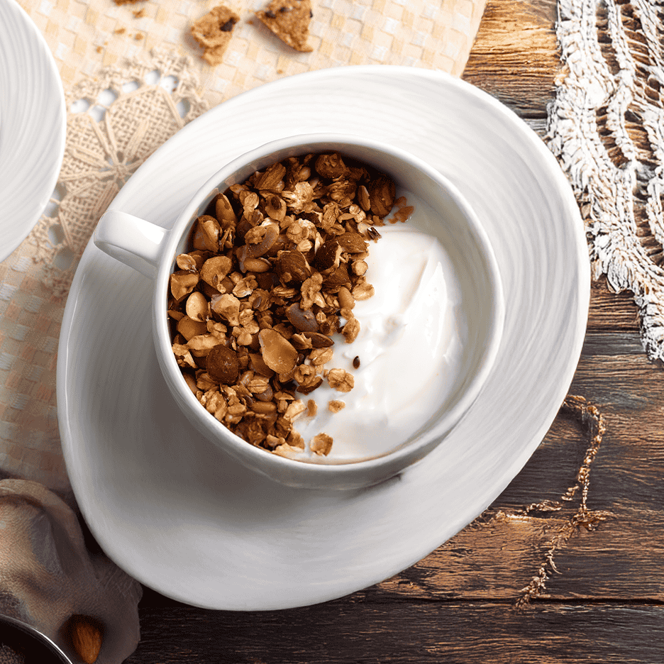 En skål med yoghurt og granola på et træbord med en hvid dug.