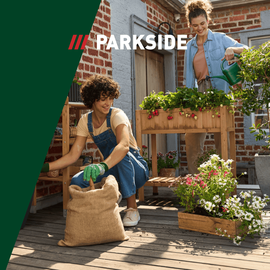 To kvinder planter og vander jordbær og blomster på en træterrasse.