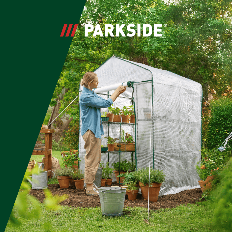 Kvinde justerer et drivhus fyldt med potteplanter og urter i en have.