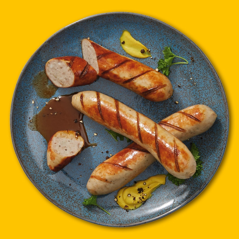 Grillede pølser med sennep, sovs og persille på en blå tallerken.