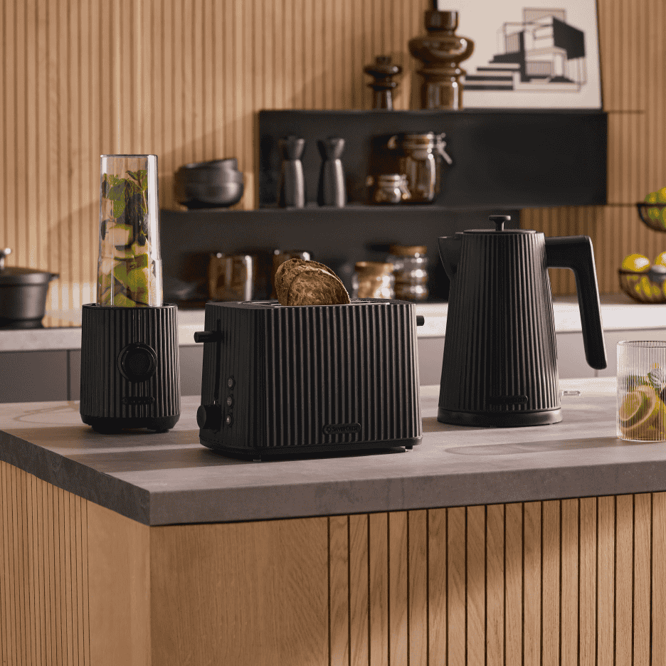 Sort stribet blender, brødrister og elkedel på et køkkenbord.