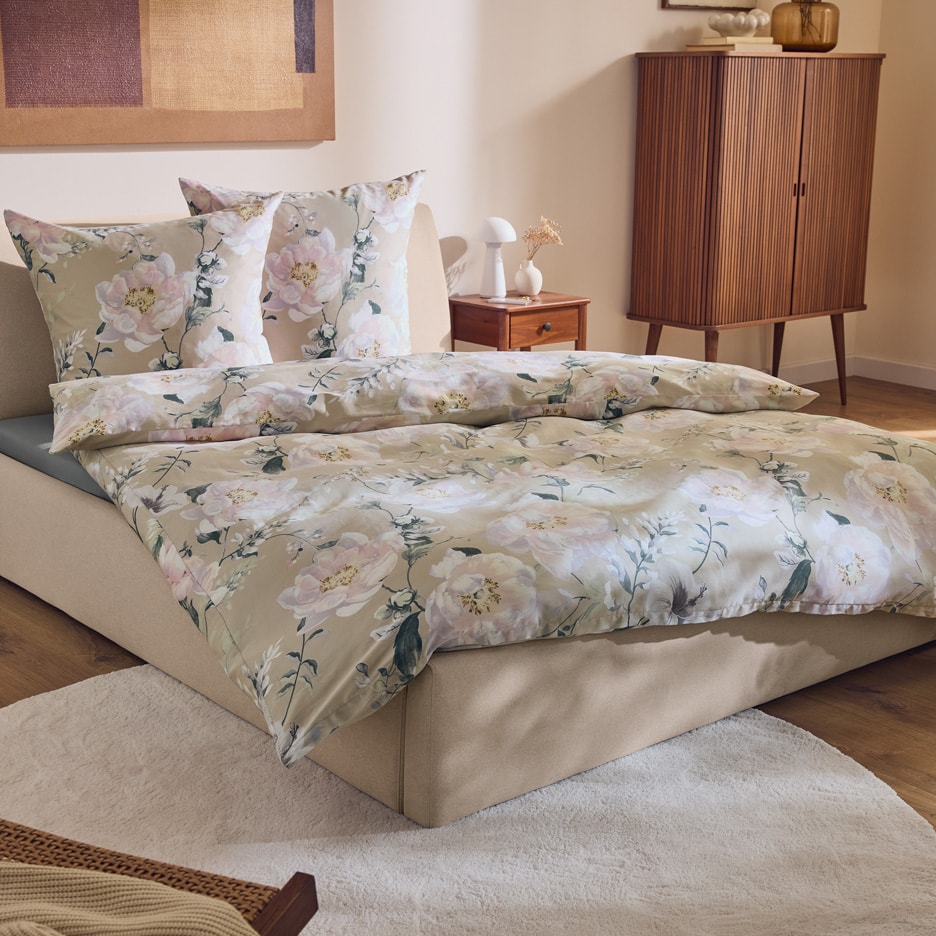 Senge med blomstret sengetøj i et soveværelse med træmøbler.