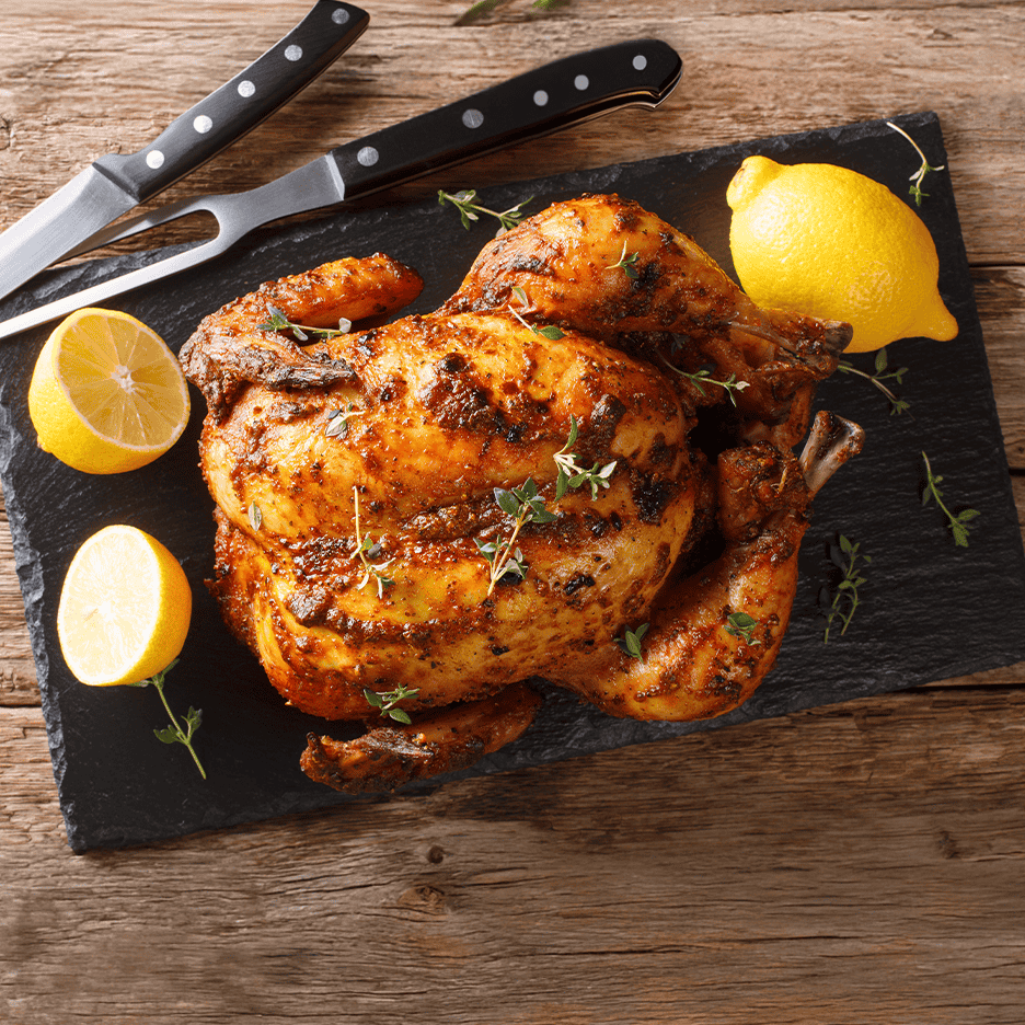 Helstegt kylling med citron og timian på en sort skiferplade