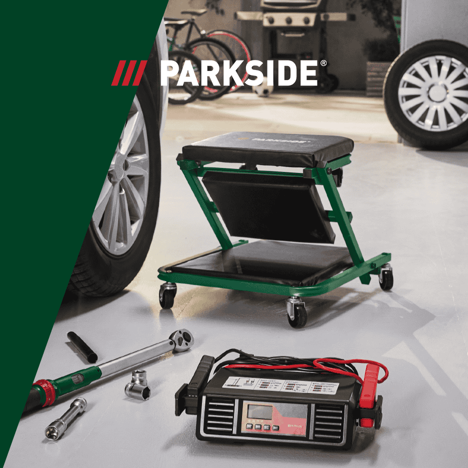 Værktøj og udstyr til bilreparation, herunder en mekanikervogn, momentnøgle og batterioplader.