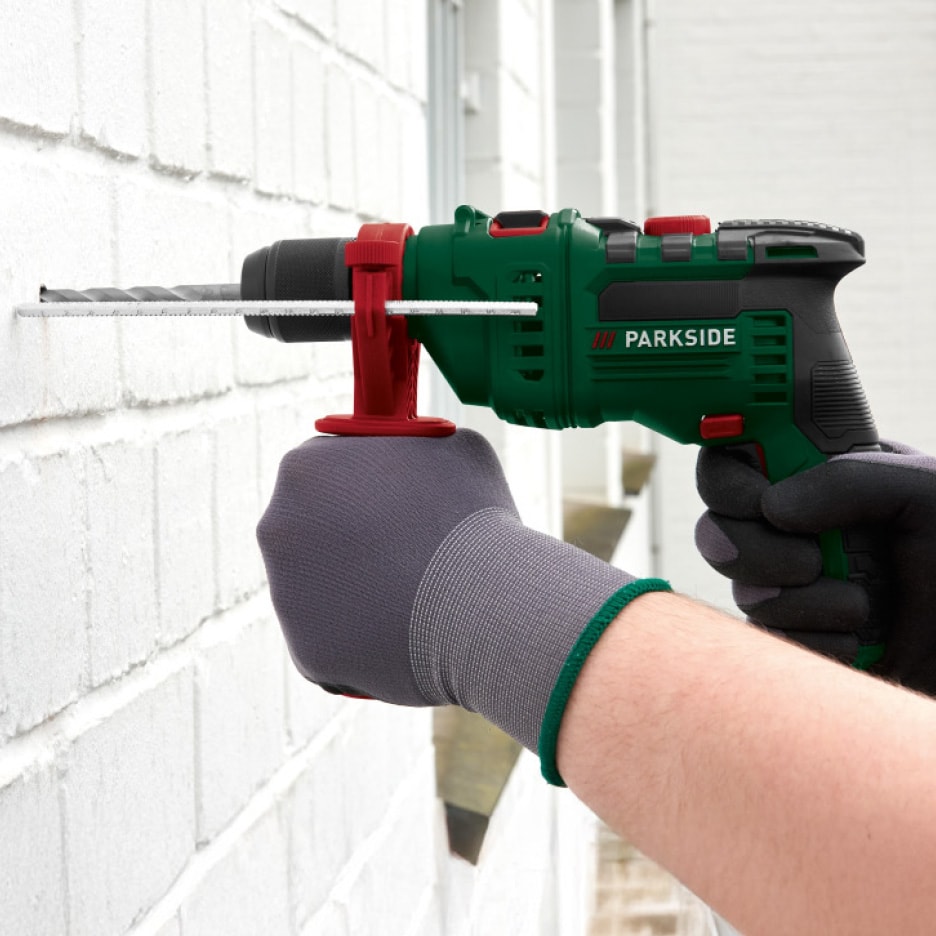 Parkside boremaskine borer i en hvid murstensvæg.
