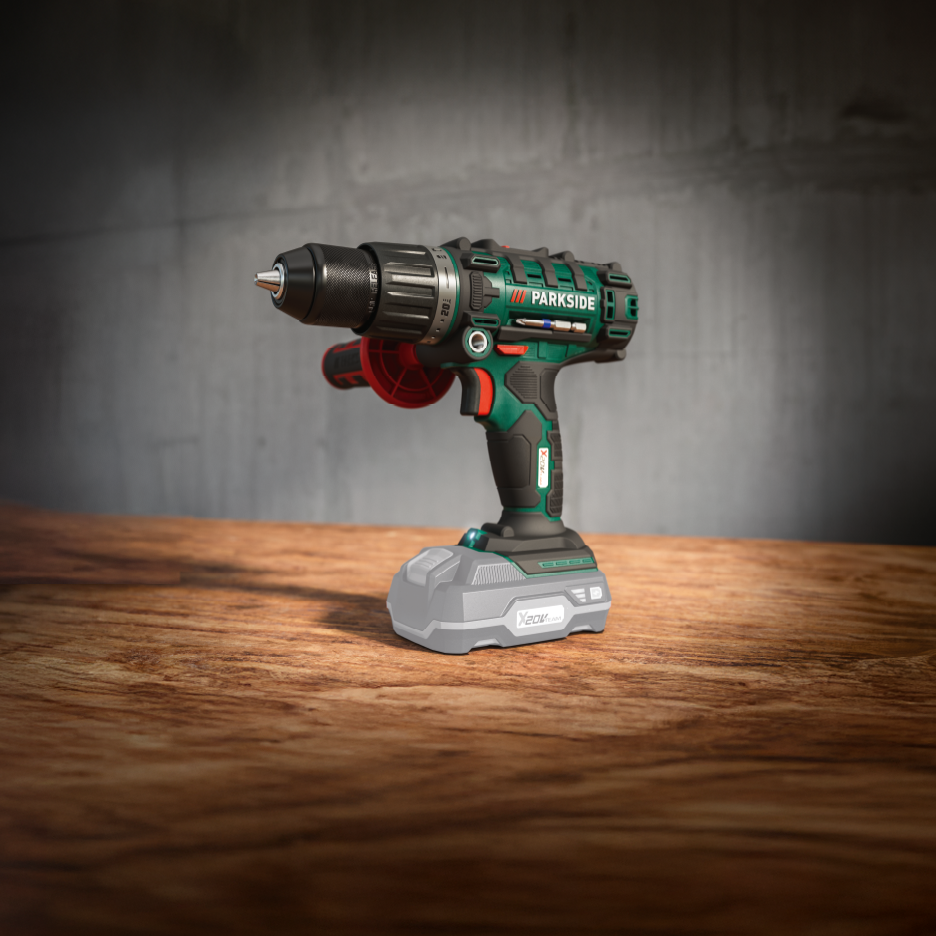 Grøn og sort boremaskine med et gråt batteri på et træbord foran en grå væg.