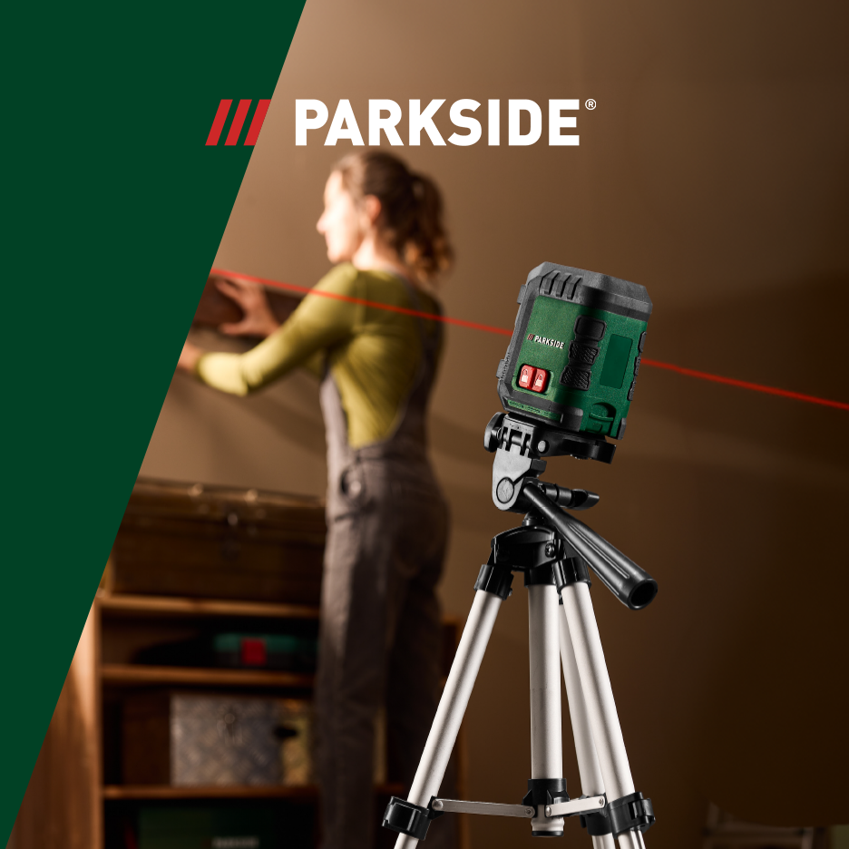 Laserudstyr på stativ med en kvinde, der bruger en laser til at måle en væg.