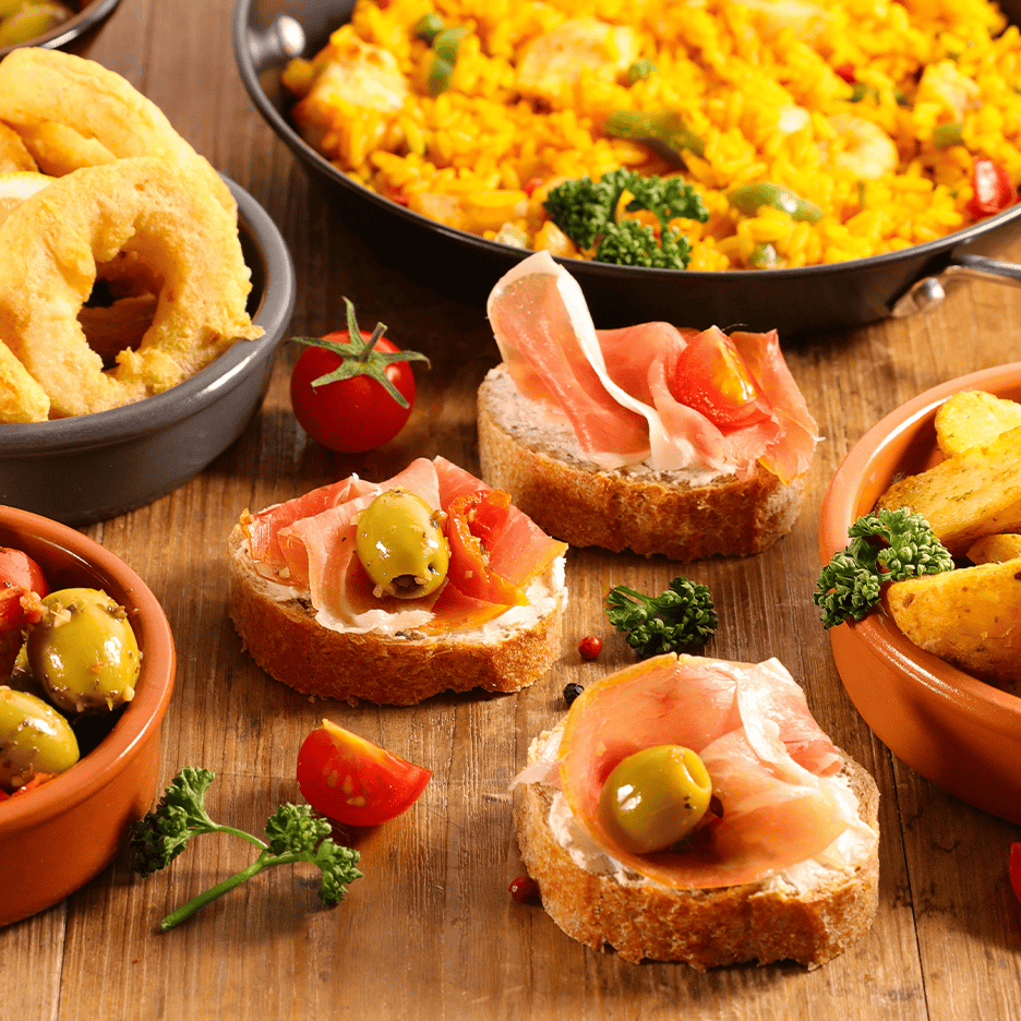 Spansk tapasbord med paella, calamari, bruschetta med skinke og oliven samt patatas bravas.