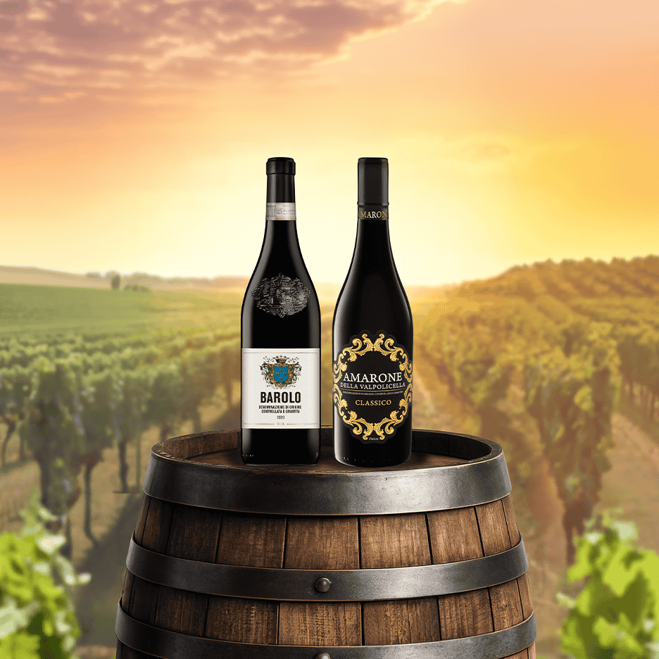 To flasker rødvin, Barolo og Amarone Classico, på en vintønde i en vingård ved solnedgang.