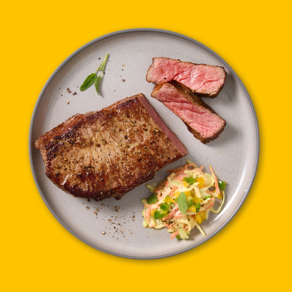 Bøf med coleslaw og salvie på en grå tallerken.