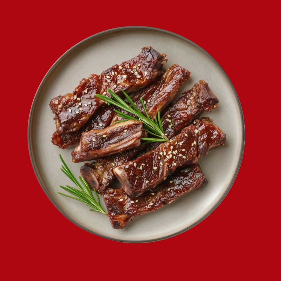 Grillmarinerede spareribs med sesamfrø og rosmarin på en tallerken.