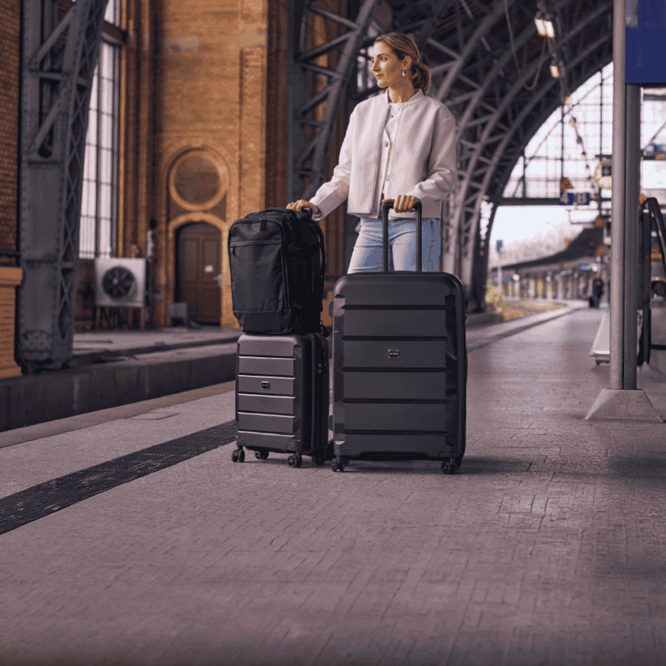 Kvinde med tre sorte kufferter på en togperron.