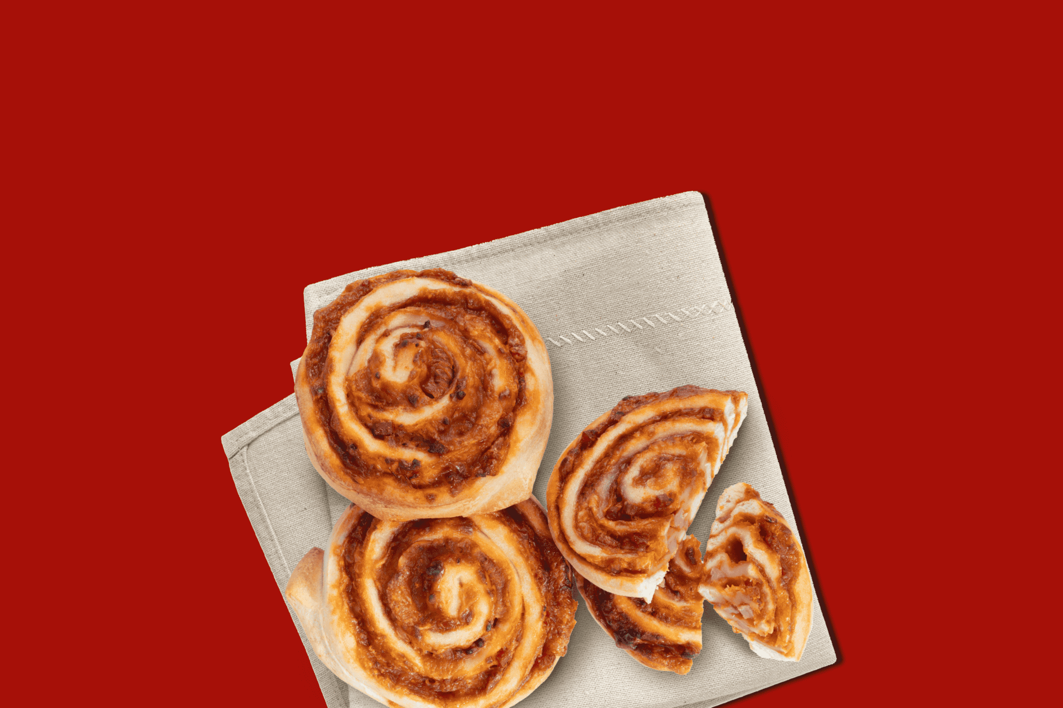 Pizzasnegle på et beige klæde, med to hele og en delt i stykker, på en rød baggrund.