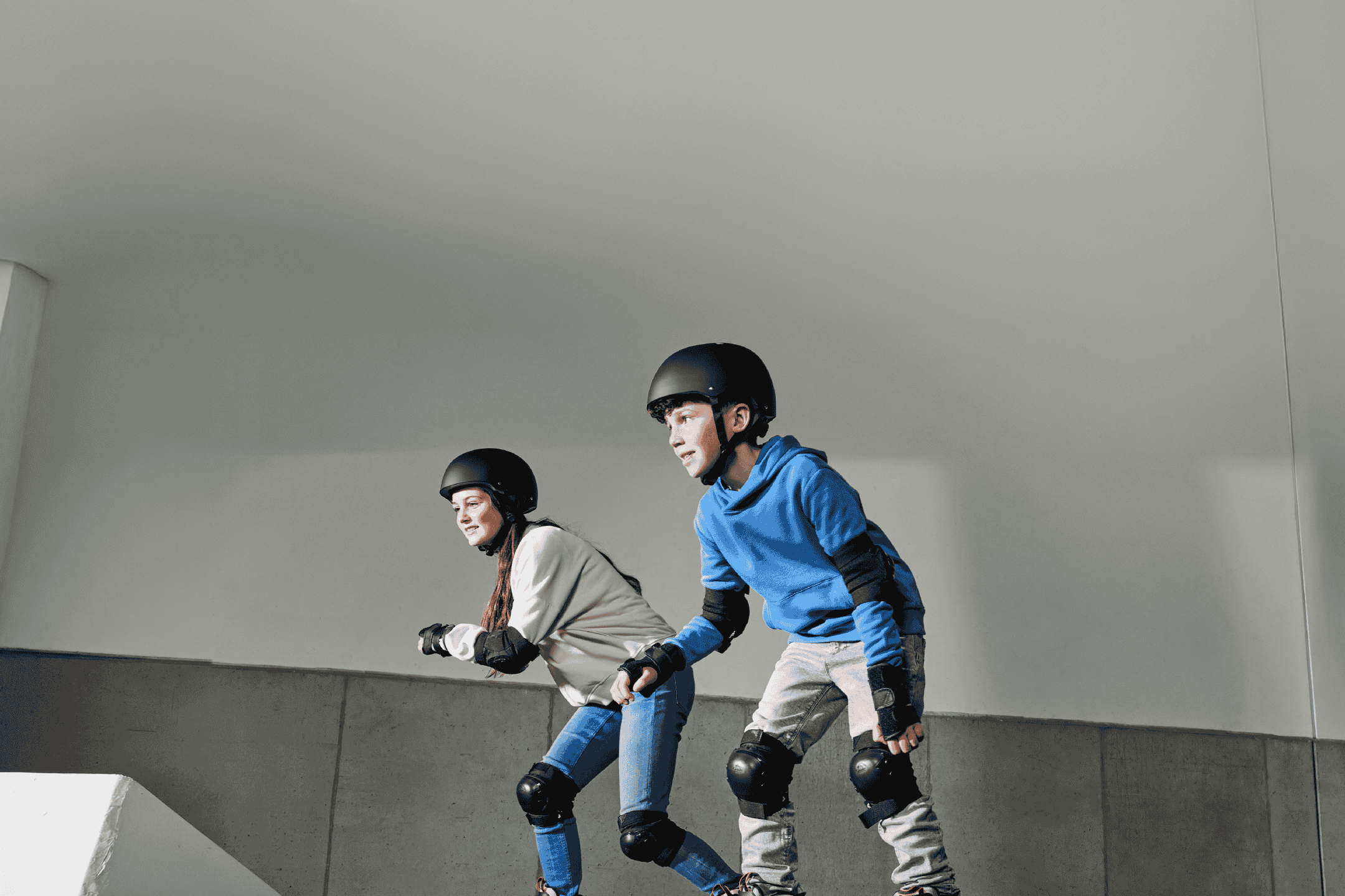 To børn på rulleskøjter med hjelme og beskyttelsesudstyr.