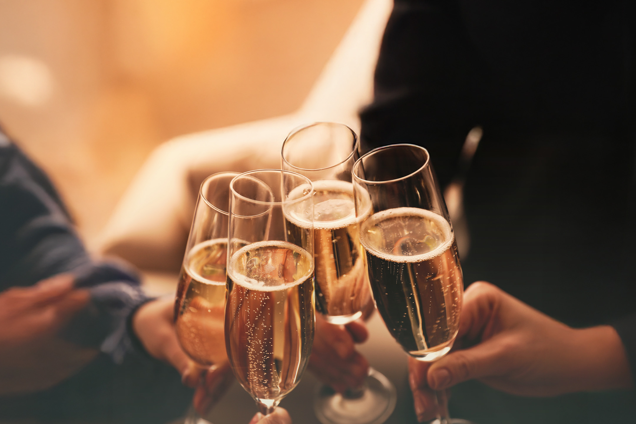 Fem personer skåler med champagneglas fyldt med mousserende vin.