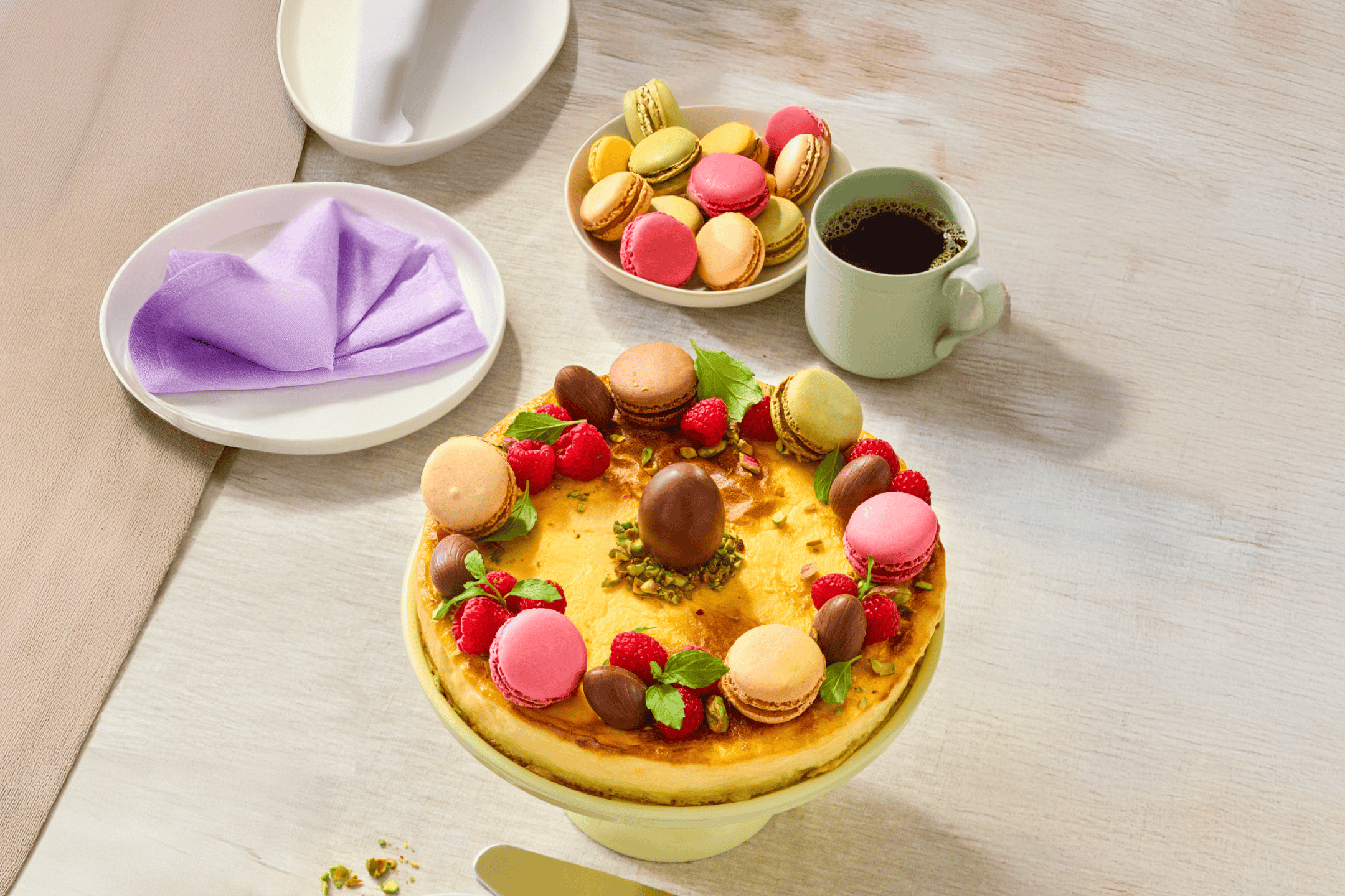 Cheesecake med makroner, hindbær og chokoladeæg, serveret med kaffe og makroner.