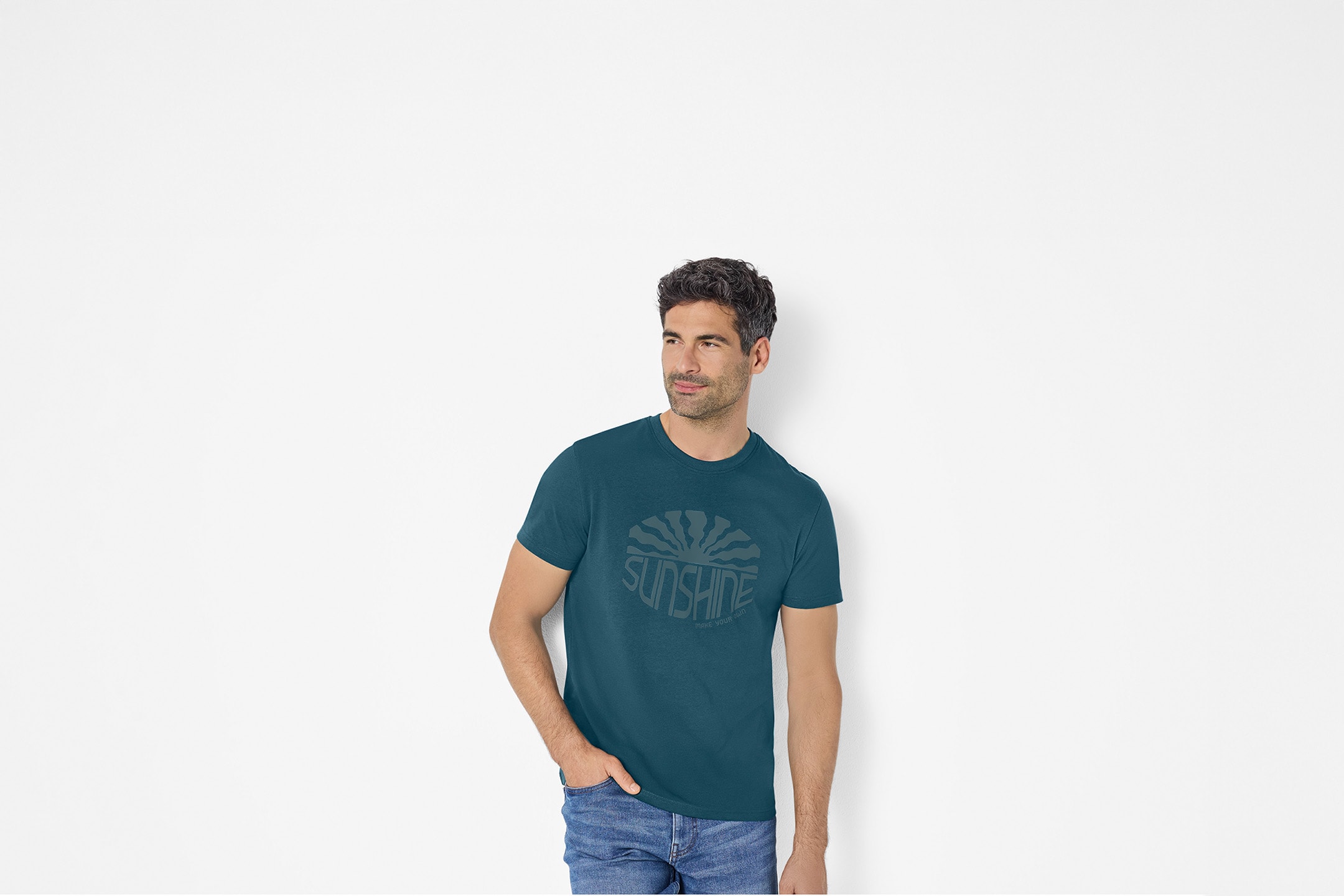 Mand i mørkeblå T-shirt med 'SUNSHINE make your own sun' print og jeans.