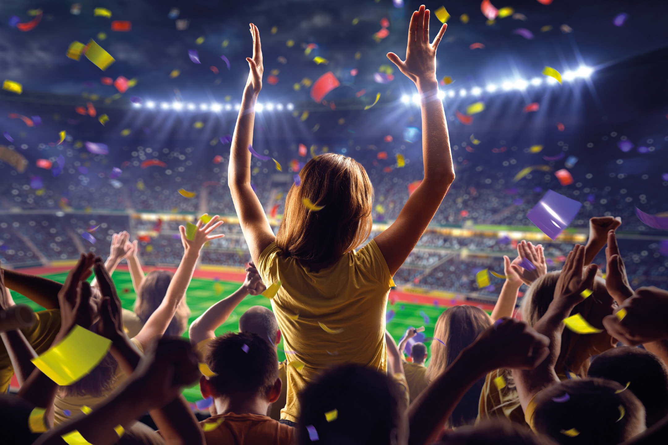 Jublende fans i et stadion med konfetti, set bagfra.